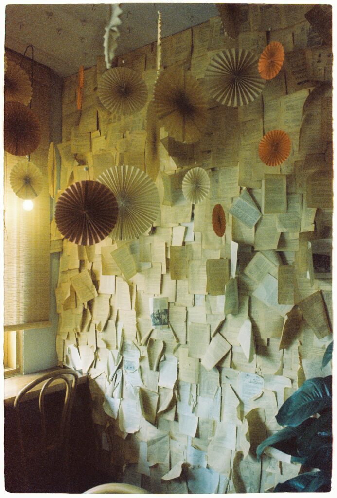 A cozy indoor scene featuring a wall covered in paper with hanging decorations, artistic ambiance.