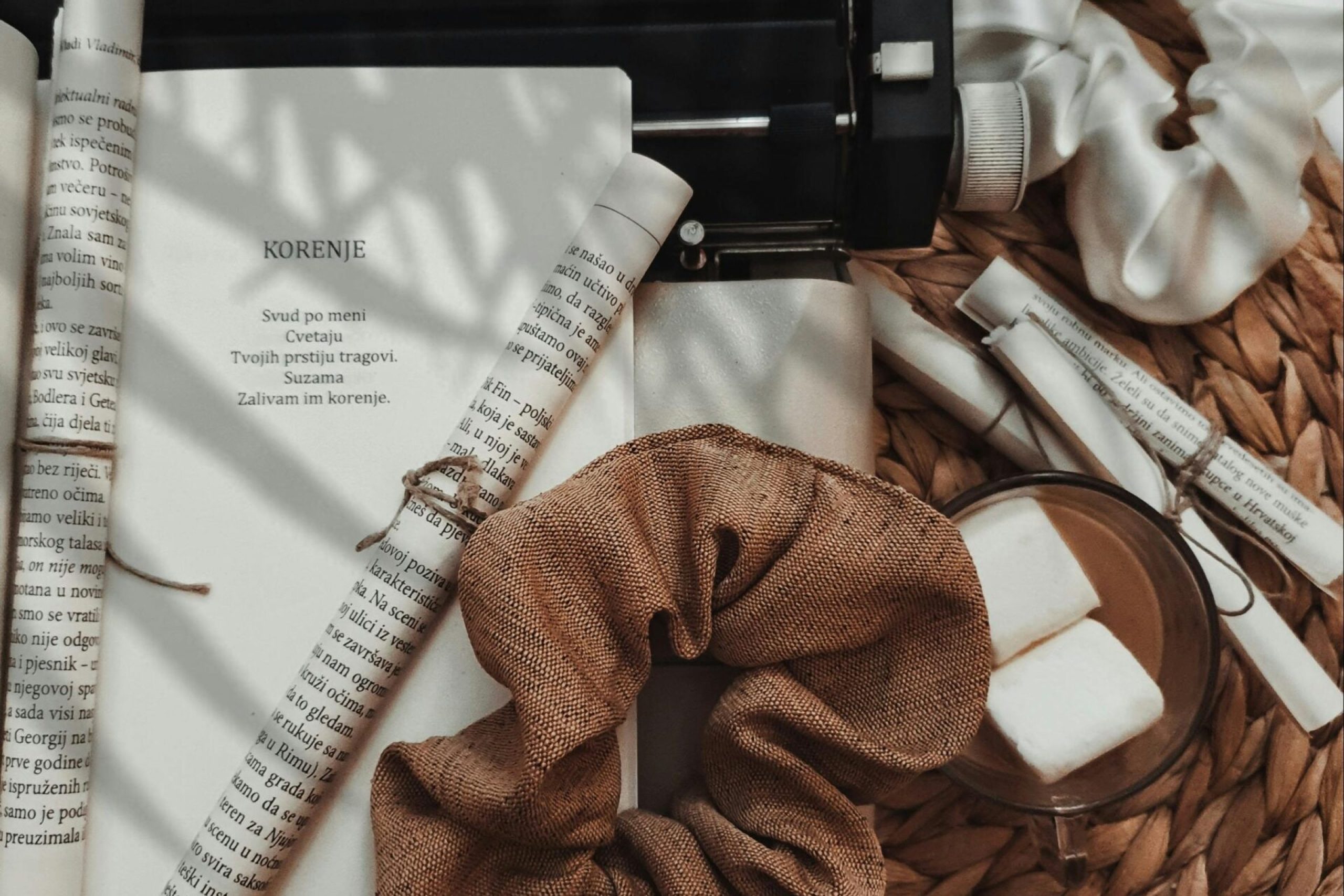 A creative flat lay of a vintage typewriter surrounded by paper rolls and scrunchies, set against a woven background.